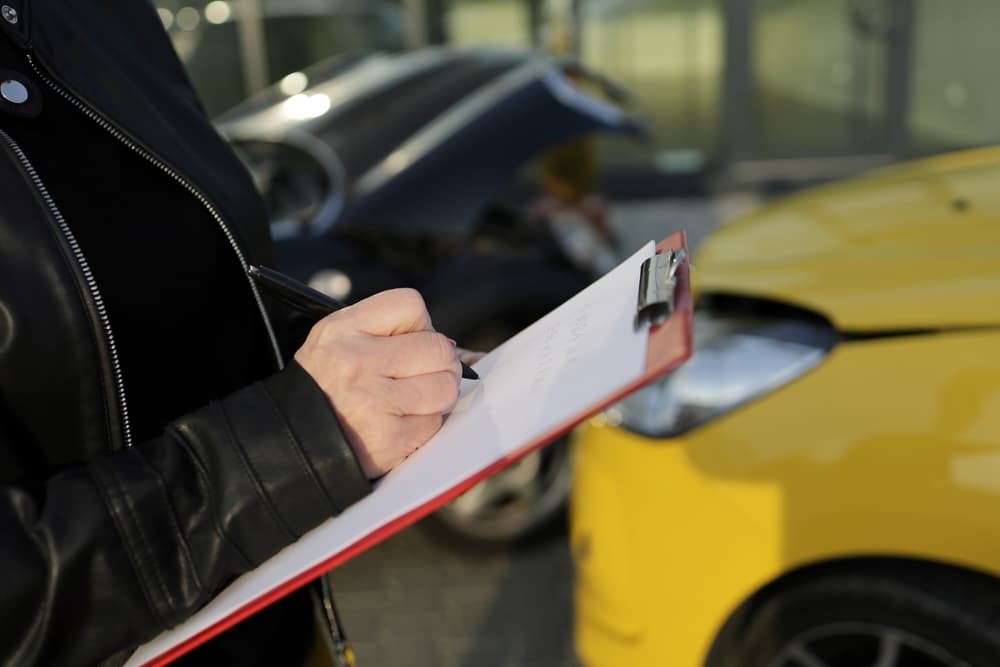 A woman recording a car accident between a black and a yellow car