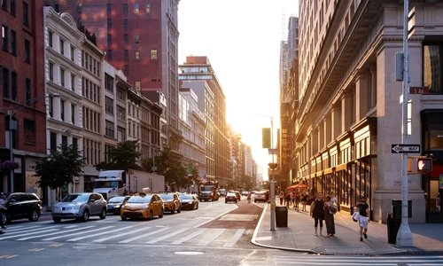 Busy city street scene at sunset with pedestrians and traffic, highlighting typical urban congestion.