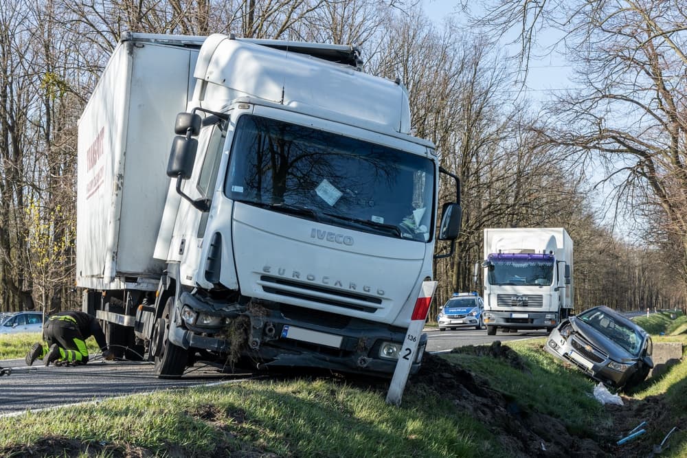 A damaged truck off the road with another car in a ditch after an accident.